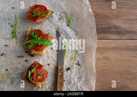 Deliziosa casa bruschetta con grano intero pane pomodoro grigliate e rucola fresca. Vegetariano snack sani, cibo vegan Foto Stock