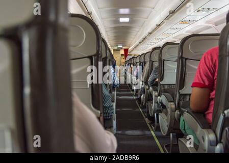 Corridoio a piedi e i passeggeri di classe economy cabina in aereo Foto Stock