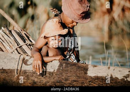 MADAGASCAR OTTOBRE 18.2016 donna malgascia con bambini dal villaggio di trasporto da tradizionale a mano piroga imbarcazione in legno. Vita quotidiana su r Foto Stock