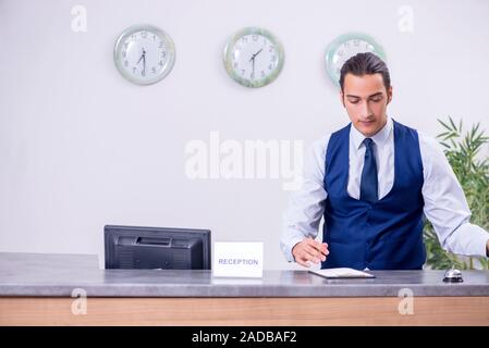 Il giovane addetto al ricevimento presso l'hotel counter Foto Stock