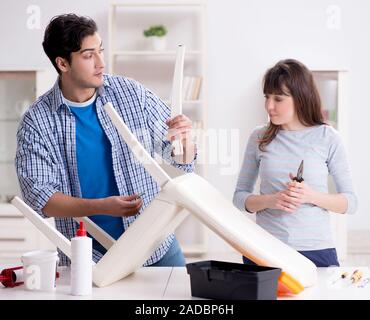 Moglie aiutando il marito per riparare sedia rotta a casa Foto Stock