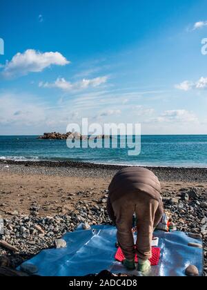 Donna Sciamano eseguendo shamanist rituale, ocean beach, vicino underwater tomba del re Munmu di Silla, segnato da rocce Daewangam, Gyeongju, Corea del Sud Foto Stock