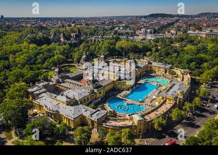 Budapest, Ungheria - Aerial drone vista del famoso Szechenyi Bagno Termale e Spa su una soleggiata giornata estiva. Piazza degli Eroi e Castello Vajdahunyad a bac Foto Stock