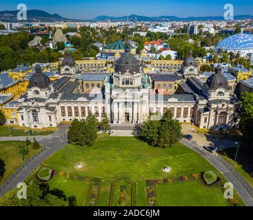 Budapest, Ungheria - Aerial drone vista del famoso Szechenyi bagno termale nel parco cittadino (Varosliget) su una soleggiata giornata estiva con cielo azzurro e GRE Foto Stock