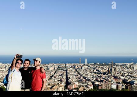 Barcellona, Spagna - Agosto 15, 2016: un gruppo di persone che prendono un selfie con uno smartphone sulla cima di una collina con la città di Barcellona al di sotto di esse Foto Stock