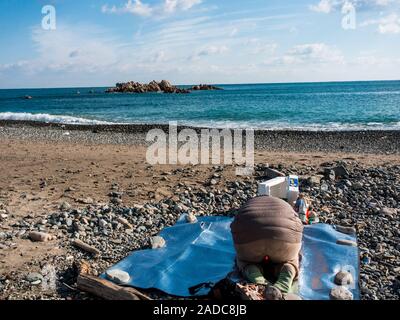 Donna Sciamano eseguendo shamanist rituale, ocean beach, vicino underwater tomba del re Munmu di Silla, segnato da rocce Daewangam, Gyeongju, Corea del Sud Foto Stock