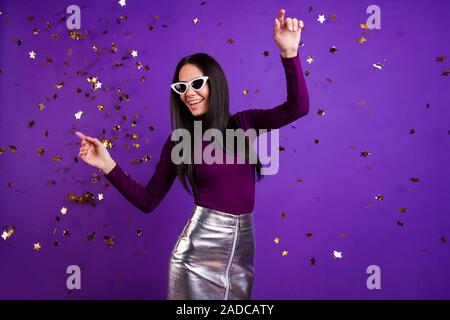 Foto di elegante carino bella bella donna affascinante in ballo la caduta di coriandoli che frequentano night club isolato vibrante colore sfondo viola Foto Stock