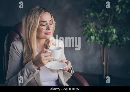 Foto di incantevole carino dolce carina ceo godendo di tazza di caffè in occhiali aventi il resto dopo aver consultato i suoi operai circa lo sviluppo di nuovi Foto Stock