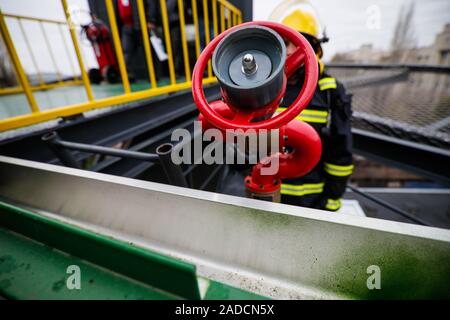 Dettagli con le mani di un vigile del fuoco in possesso di un sistema antincendio idranti () su un ospedale helipad. Foto Stock