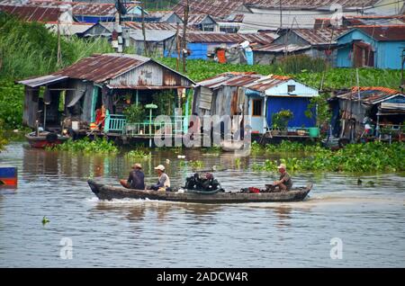 Una barca pwers passato case fatte dal ferro corrugato sul fiume Mekong in Chau Doc nel Delta del Mekong in Vietnam del sud Foto Stock