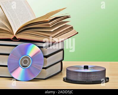 Pila di libri e dischi DVD come simboli di vecchi e nuovi metodi di memorizzazione delle informazioni Foto Stock