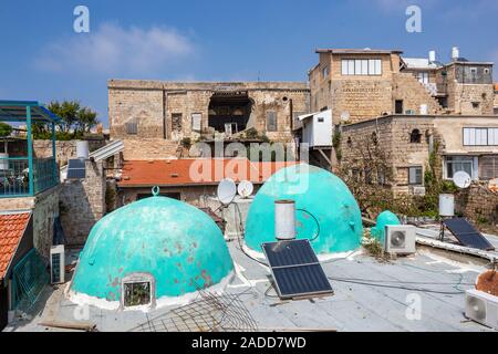 Strade della città vecchia di acri in Israele, sui tetti di cupole azzurre e pannelli solari in background la vecchia casa Foto Stock