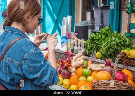 Una ragazza prende una foto sul mercato ad Acri dove il venditore vende di menta fresca e agrumi. Ella fa le foto per il suo blog. Foto Stock