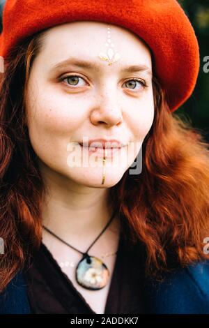 Giovane e bella red sentire la donna in un mantello blu e berretto rosso cercando e sorridente Foto Stock