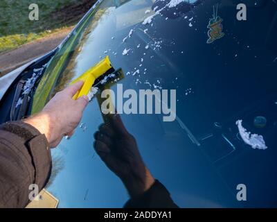 Guida invernale - la raschiatura di ghiaccio da un parabrezza presi in un freddo gelido mattina Foto Stock