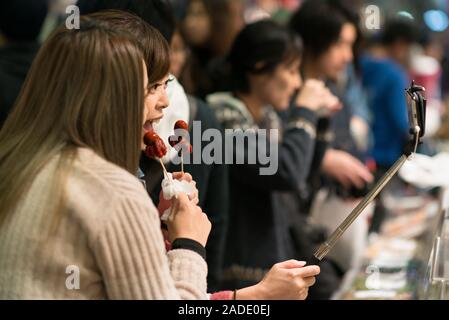 Kyoto, Giappone - 03 Novembre 2018: due donne che prendono un selfie tenendo un Tako tamago spiedino al mercato Nishiki a Kyoto. Tako tamago è una strada popolare Foto Stock