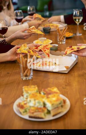 Felice co-lavoratori celebra durante la festa aziendale, per eventi aziendali. Giovani uomini caucasici in abbigliamento business parlare, bere vino e mangiare spuntini. Concetto di ufficio cultura, il lavoro di squadra, amicizia, weekend. Foto Stock