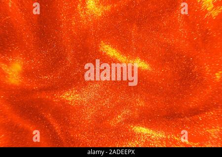 Abstract elegante, dettagliata luminosi rosso e oro glitter flusso di particelle con profondità di campo ridotta sott'acqua. Vacanza magica scintillante backgrou di lusso Foto Stock