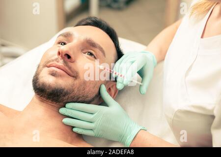 Dottore in guanti di gomma rendendo iniezione per il giovane Foto Stock