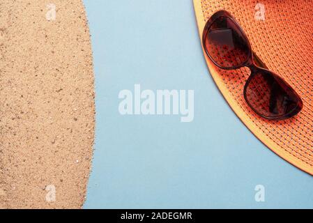 Accessori da spiaggia sulla sabbia su sfondo blu con una copia dello spazio. La vacanza estiva concetto. Foto Stock