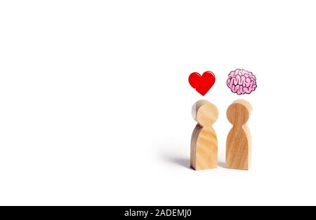 Due figure in legno con l'immagine del cervello e cuore. L'equilibrio tra amore e mente. La famiglia rispetto alla carriera o al lavoro. La psicologia della famiglia. Problema Foto Stock