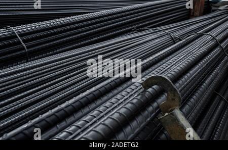 Edificio ancora nel magazzino dei prodotti metallurgici o sul sito in costruzione. Pila di metalli pesanti barre di rinforzo con profilo periodico Foto Stock