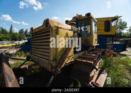 Vecchio giallo arrugginito trattore in campo nella giornata di sole. Foto Stock
