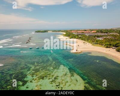 Vista aerea della spiaggia di Nusa Dua a Bali Indonesia con baia e un mare turchese sopra presa dal mare durante il mese di aprile con un drone Foto Stock