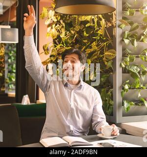 Piacevole ragazzo impegnato in seduta cafe, vedendo i suoi amici Foto Stock