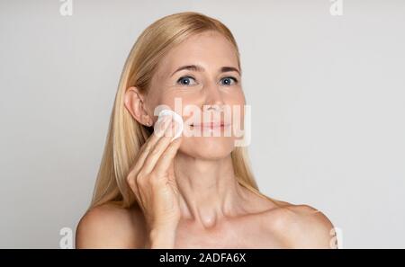 Rimuovere il trucco. Positivo donna di mezza età con tampone di cotone Foto Stock