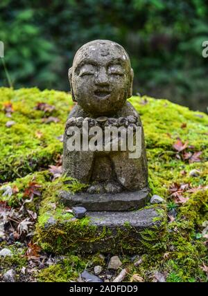 Statue di pietra di sorridere Jizo Bosatsu con muschio verde al giardino zen nel Sanzen-in tempio, Kyoto, Giappone. Foto Stock