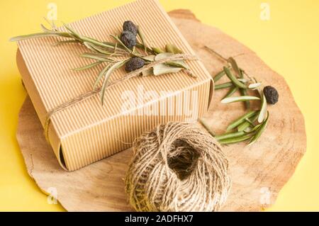 Rifiuti Zero idee regalo. Giftbox si inginocchiò con cavo e olive branch su sfondo di legno e copyspace. Foto Stock