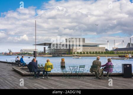 La città di Copenhagen, vista della coppia di turisti seduti sul Playhouse Theatre terrazza e guardare al di là del porto alla Opera House di Copenhagen, Danimarca. Foto Stock