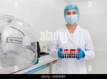 Donna in medical indossare la preparazione di campioni di sangue in tubi di prova Foto Stock