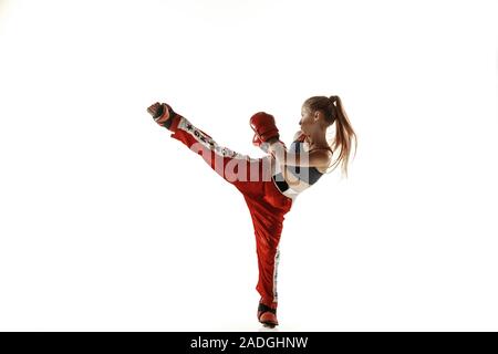 Giovani femmine kickboxing fighter training isolati su sfondo bianco. Caucasian ragazza bionda in rosso sportswear pratica nelle arti marziali. Concetto di sport e stile di vita sano, motion, azione Gioventù. Foto Stock