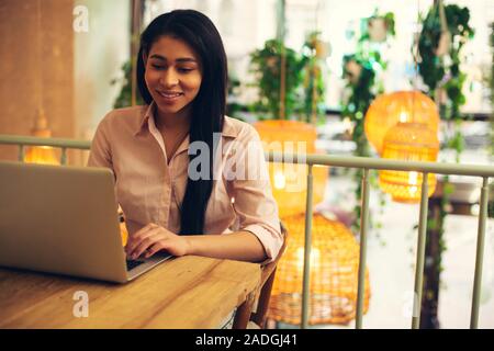 Giovane e bella signora sorridente e guardando lo schermo Foto Stock