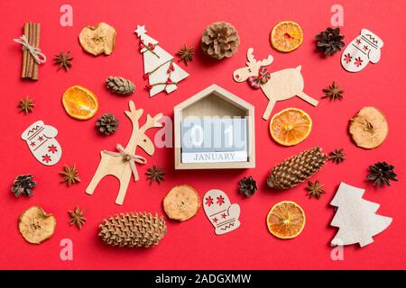 Vista superiore del calendario, sfondo rosso decorato con giocattoli di festosa e simboli di natale renne e nuovo anno alberi. Il primo di gennaio. Holiday con Foto Stock