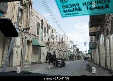 Hebron, West Bank. 4 dicembre, 2019. Palestinesi guidare un carro trainato da cavalli a Hebron. Difesa israeliano Ministro Bennett ha recentemente annunciato la sua approvazione della costituzione di un nuovo quartiere ebraico nella prevalentemente città palestinese di Hebron nei pressi del vecchio mercato di frutta e verdura. I terreni acquistati dagli ebrei che vi risiedono nei primi anni del XIX secolo, fu abbandonato dopo il 1929 massacro in cui 67 ebrei furono assassinati dai rivoltosi arabi. Credito: Nir Alon/Alamy Live News. Foto Stock