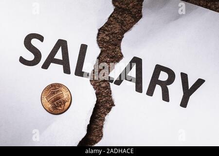 Un foglio di carta bianca con le parole lo stipendio strappata a metà. Salari bassi nella popolazione, vista dall'alto Foto Stock