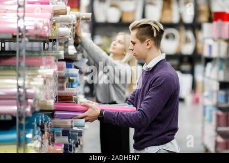 Carino giovane ragazzo e ragazza scegliere carta per la confezione regalo per vacanze invernali Foto Stock