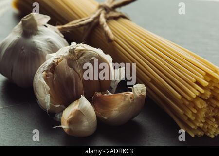 4 spicchi di aglio che giace accanto alle materie spaghetti mazzetto Foto Stock