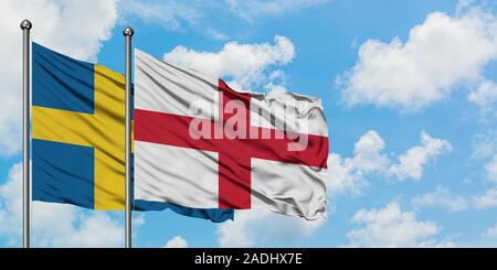 La Svezia e Inghilterra bandiera sventolare nel vento contro bianco torbido cielo blu insieme. Concetto di Diplomazia e relazioni internazionali. Foto Stock