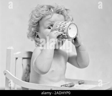 1930s BABY BOY IN SEDUTA ALTA capelli di bere dalla tazza CHE COPRONO LA MAGGIOR PARTE DEL SUO VOLTO che spuntavano con un occhio guardare fotocamera - f4798 HAR001 HARS CASEIFICIO spazio copia di metà lunghezza MASCHI A COPERTURA B&W contatto visivo bevanda divertente il suo fluido ricci comico consapevole connessione commedia MUG consumano consumando l'IDRATAZIONE BABY BOY CRESCITA JUVENILES UN OCCHIO proteina sete rinfrescanti bevande assetata in bianco e nero di etnia caucasica HAR001 in vecchio stile Foto Stock