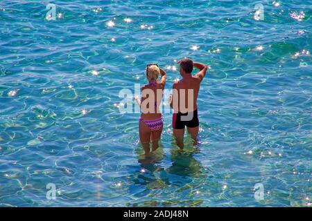 Coppia giovane in piedi in acqua poco profonda a spiaggia balneare di Sant Elm, San Telmo, Maiorca, isole Baleari, Spagna Foto Stock