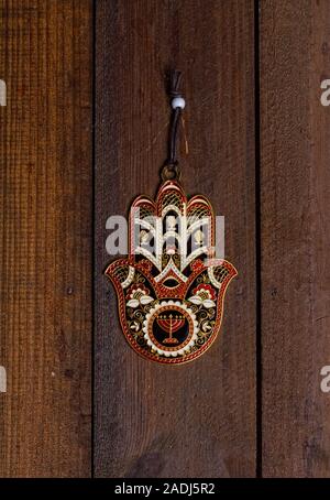 Amuleto protettivo Hamsa Fatima mano con un bel disegno appeso su una ruvida porta in legno Foto Stock