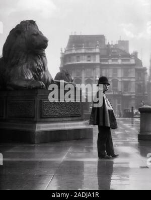 1930s WET LONDON BOBBY INDOSSANDO INGRANAGGIO DI PIOGGIA IN PIEDI DA LANDSEER LIONS IN Trafalgar Square Londra Inghilterra - r7648 HAR001 HARS PERSONE ISPIRAZIONE MASCHI DI PIOVERE OFFICER INGLESE B&W GRAN BRETAGNA COP proteggere e servire i Lions protezione autorità di scultura di occupazioni uniformi BOBBY concettuale Ufficiali Carabinieri CITY OF WESTMINSTER LA COOPERAZIONE COPS giovane adulto uomo BADGE BADGE IN BIANCO E NERO di etnia caucasica GRAN BRETAGNA HAR001 LANDSEER in vecchio stile TRAFALGAR REGNO UNITO Foto Stock