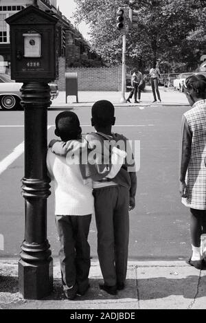 Anni sessanta VISTA POSTERIORE DUE GIOVANI ANONIMO STAGLIANO AFRICAN AMERICAN BOYS A BRACCETTO IN ATTESA DI CROSS STREET AL SEMAFORO - s17241 HAR001 HARS CARING Pericolo rischio maschi fratelli fiducia B&W avventura strategia di protezione stagliano afro-americani afro-americano a braccetto nero etnia al di pari livello concettuale di collegamento supporto luce sul traffico anonimo il supporto di assistenza vista posteriore la crescita novellame convivere IN BIANCO E NERO HAR001 in vecchio stile afro-americani Foto Stock