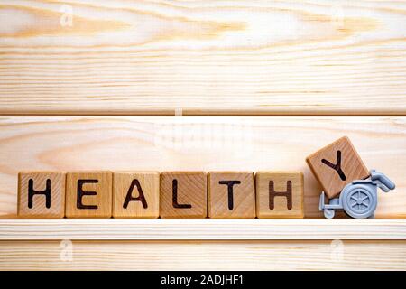 Una sana parola fatta di cubetti di legno su uno sfondo di legno. Segno sano, il concetto di medicina. Il concetto di assistenza sanitaria. La parola scritta sani con cubetti di legno. Medicina Preventiva concetto. Uno stile di vita sano Foto Stock