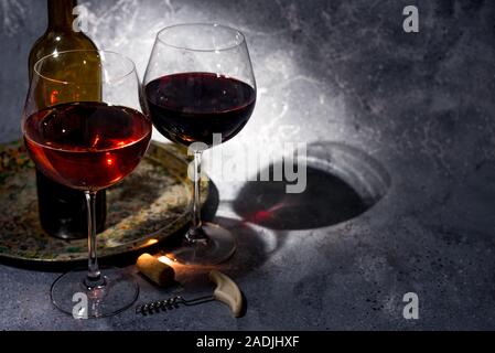 Vino rosso. Bottiglia e bicchiere di vino rosso. In stile vintage. Vino rosso su sfondo nero. Design con lo spazio per il tuo testo. Foto Stock