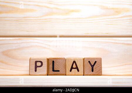 Gioco di parole scritte su cubi di legno su sfondo di legno. Cubi di legno formata la parola play. Online, gioco drammatico. Per il legno lettere latine ha fatto il gioco di parola Foto Stock